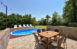 A backyard with a swimming pool, lounge chairs, a dining table, and a wooden deck. - Cozy home in Biskupec Zelinski with sauna (Biskupec Zelinski)