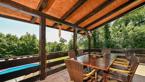 An outdoor patio with a wooden table and wicker chairs, overlooking a swimming pool and lush greenery. - Cozy home in Biskupec Zelinski with sauna (Biskupec Zelinski)