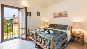 Een slaapkamer met een bed, twee nachtkastjes, een raam met uitzicht en een deur naar een buitenruimte.