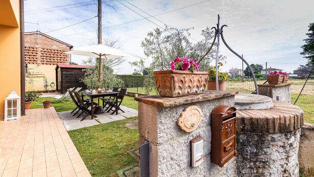 Een terras met een tafel, stoelen, een brievenbus en een huisnummer.