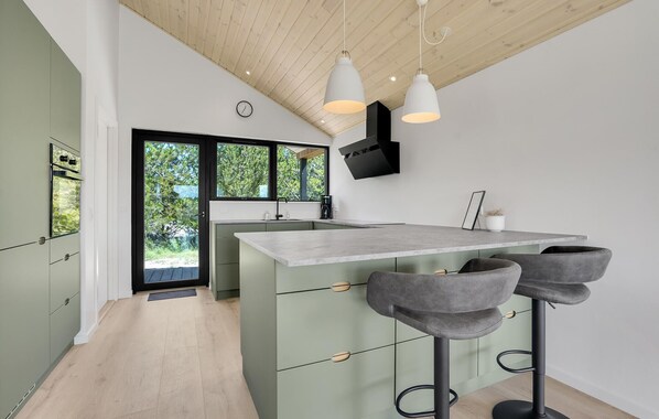 A modern kitchen with a large island, bar stools, and a view of greenery outside. - 3 bedroom stunning home in Jerup (Jerup)