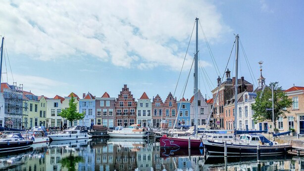 Een jachthaven met aangemeerde boten, omgeven door kleurrijke gebouwen met traditionele architectuur.
