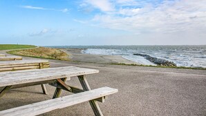Een houten picknicktafel aan een verhard pad, met uitzicht op de zee.
