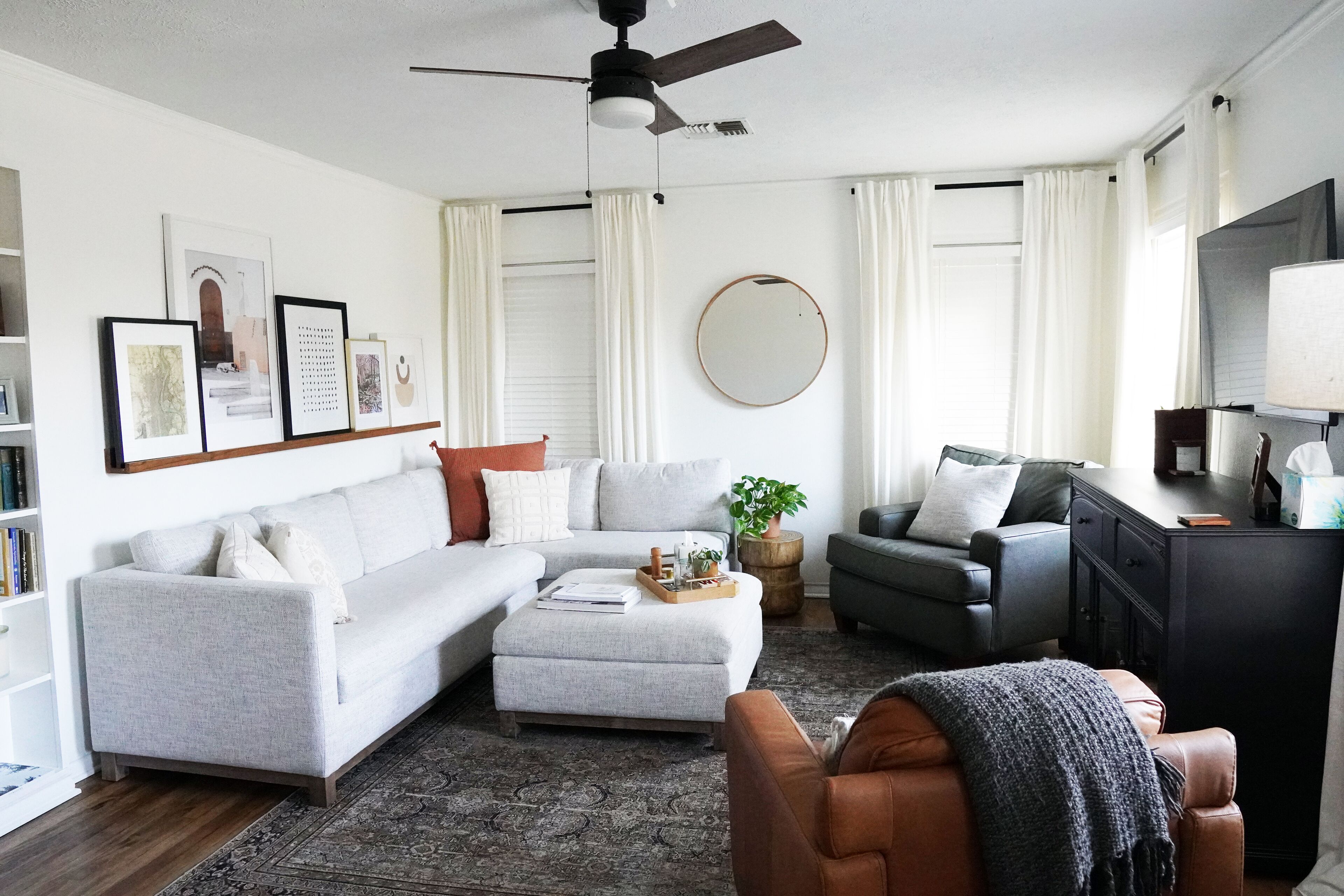 A living room with a grey sofa, a brown leather chair, a coffee table, and a TV stand.