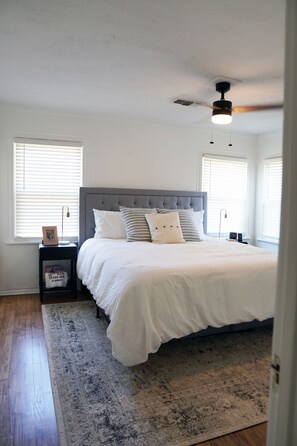 A bedroom with a large bed, a ceiling fan, and a nightstand with a lamp. - The Village House - 3 bedroom, 1 bath home 1.5 mi to Texas A&M, 2 mi to Legends (Bryan)