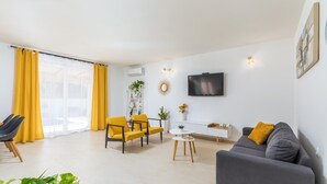 A modern living room with a grey sofa, yellow chairs, a white coffee table, and a TV mounted on the wall. - Lovely home in Valbandon (Valbandon)