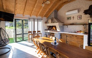 Enjoy meals by the fireplace in this inviting dining area with a table, chairs, and a hanging chair.