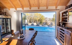 Enjoy a romantic dinner for two at this cozy dining table, overlooking the serene pool area and lush surroundings.