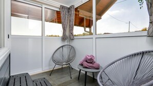 Un balcon avec deux fauteuils en osier, une petite table et une serviette enroulée.