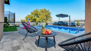 Un espace aménagé au bord de la piscine, avec une table, des chaises et un flotteur en forme de cygne.