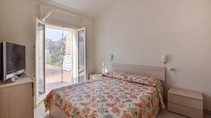 A bedroom with a bed, a TV, a bedside table, and a window with a view of the outside. - Lovely home in Valledoria with WiFi (Valledoria)
