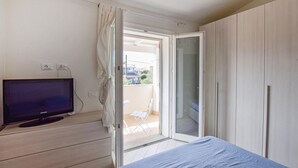 A bedroom with a bed, a TV, a sliding glass door to a balcony, and a wardrobe. - Lovely home in Valledoria with WiFi (Valledoria)