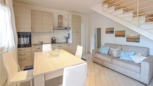 A modern kitchen with wooden cabinets, a dining table with chairs, a sofa with cushions, and a staircase. - Lovely home in Valledoria with WiFi (Valledoria)