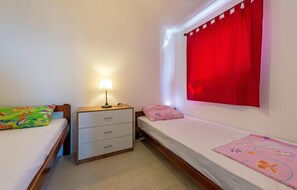 A small bedroom with two beds, a nightstand, a lamp, and a window with red curtains. - Gorgeous apartment in Vir with WiFi (Vir)
