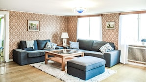 Ein Wohnzimmer mit gestreiftem Wandteppich, einer Sofagarnitur, einem Couchtisch und einer Heizung.