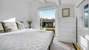 Une chambre à coucher avec un lit, une plante en pot et une vue sur l’extérieur.