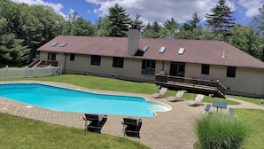 Ein zweistöckiges Haus mit Pool, überdachter Terrasse und umzäunter Garten.