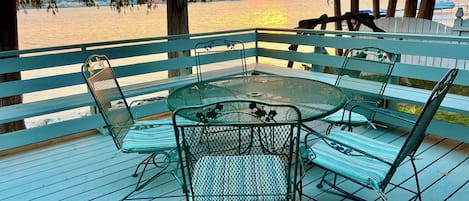 Relax in this serene outdoor seating area with a round table and six comfortable chairs, offering a view of the water and distant shoreline.