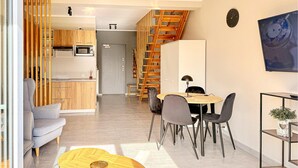 A modern kitchen with wooden cabinets, a dining area with a table and chairs, and a staircase. - 2 bedroom nice home in Grzybowo (Grzybowo)