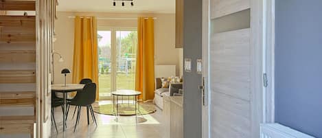 Ein modernes Interieur mit Essbereich, einer Couch und Blick durch eine Glastür auf einen Außenbereich.