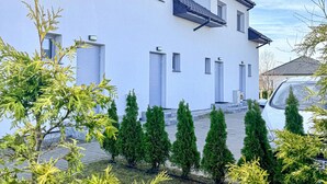 A modern two-story building with a white exterior, multiple windows, and a paved driveway. - 2 bedroom nice home in Grzybowo (Grzybowo)