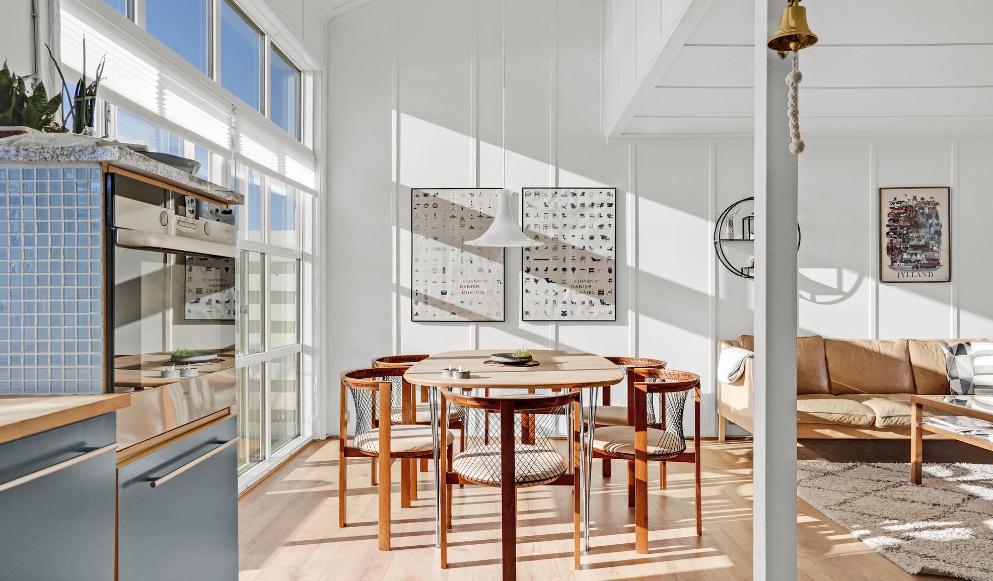 Una cocina moderna con zona de comedor, que incluye una mesa redonda y sillas, un salpicadero de azulejos azules y un ventanal grande.