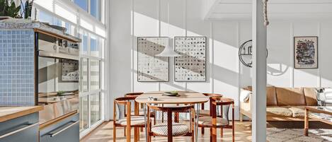 Una cocina moderna con zona de comedor, que incluye una mesa redonda y sillas, un salpicadero de azulejos azules y un ventanal grande.