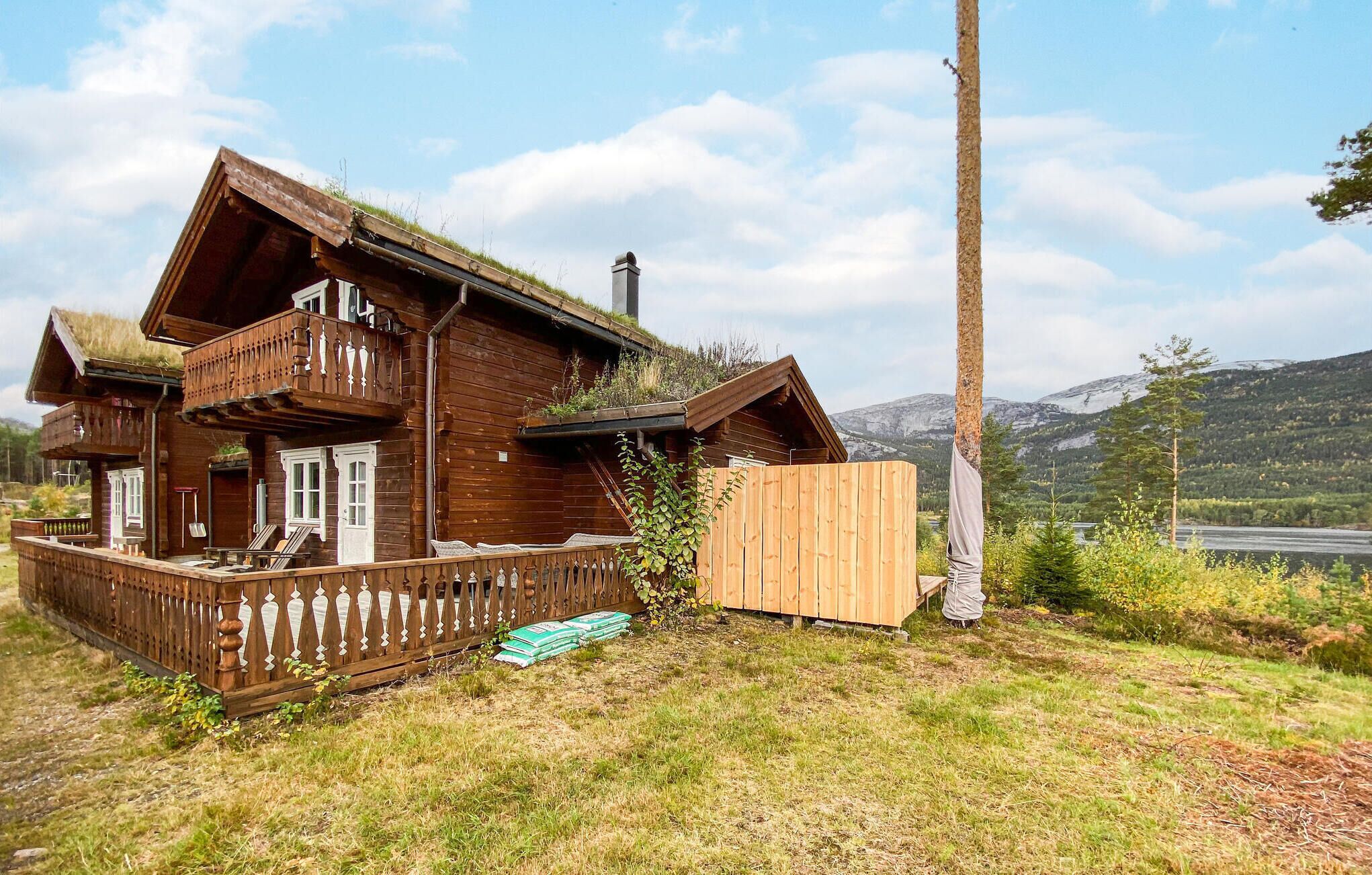 A wooden house with a balcony, a wooden fence, and a view of mountains in the background.