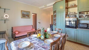Un coin repas avec une table dressée pour quatre personnes, un canapé et une cuisine équipée d’une cuisinière et d’un four à micro-ondes.