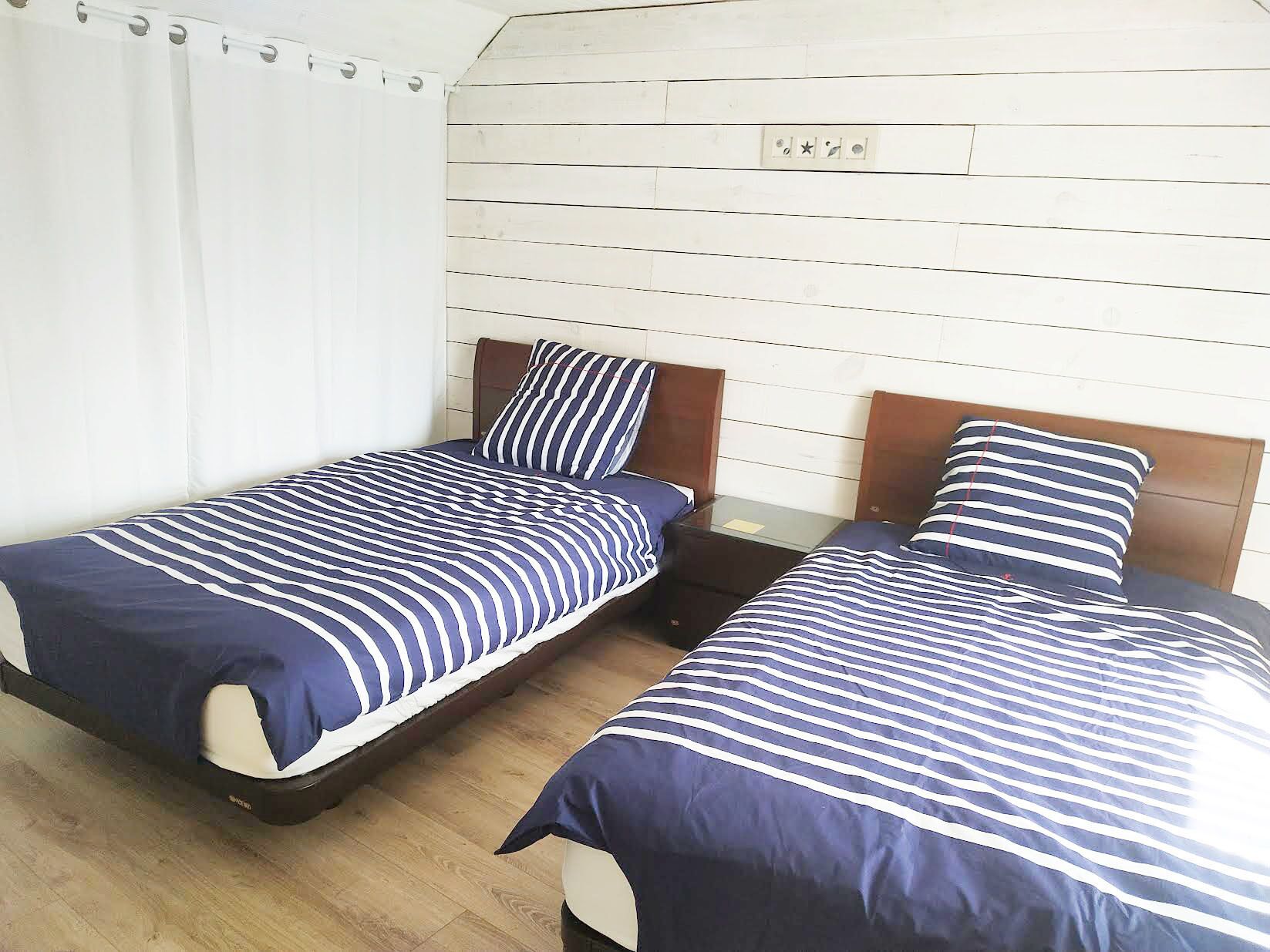 Ein Zimmer mit zwei Einzelbetten, jeweils mit einem Holz Kopfteil und gestreifter Bettwäsche.