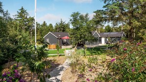 Una zona residencial con dos casas, un sendero y diversas plantas y árboles.