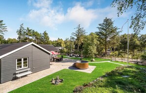 Un bâtiment moderne doté d’un toit en pente, d’un patio avec un jacuzzi et d’une pelouse bien entretenue.