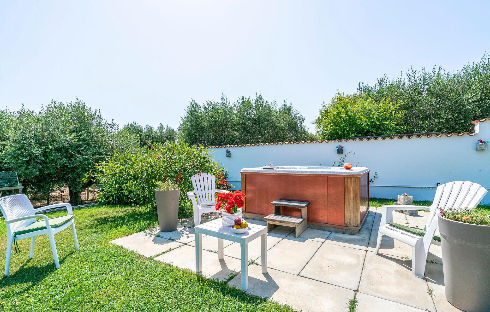 A patio with a barbecue area, white chairs, a table, and potted plants.