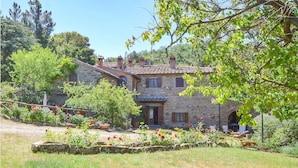 A stone house with a tiled roof, surrounded by a garden with red flowers and trees. - Cozy home in Castiglion Fiorentino (Castiglion Fiorentino)