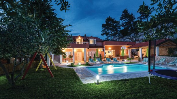 Une maison à deux étages avec une piscine, un espace salon extérieur et un panier de basketball.