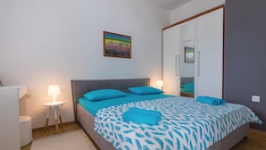 Une chambre à coucher avec un lit, une table de chevet, une lampe, un miroir et un tableau accroché au mur.