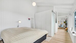 Ett sovrum med en stor säng, en sänglampa, en garderob och utsikt över matplatsen.