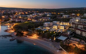 Una zona residencial costera con edificios modernos, una playa y vista al mar al atardecer.