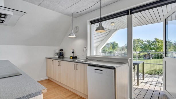 A modern kitchen with a dishwasher, a coffee maker, and a wine bottle on the counter.