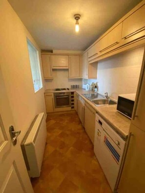 A compact kitchen with white cabinets, a built-in oven, a microwave, and a sink.