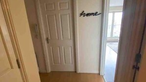 A hallway with a white door, a word 'home' on the wall, and a view through a glass door. - Apex Morrison Street Apartment (Glasgow)