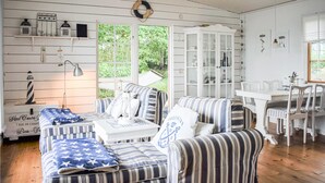 A cozy room with striped sofas, a white cabinet, and a dining table. - Amazing home in Ronneby with house sea view (Ronneby)