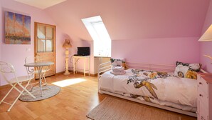 A bedroom with a bed, a desk, a chair, and a painting on the wall.