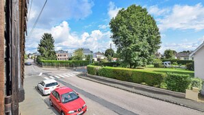 A residential street with houses, a red car parked on the side, and a pedestrian crossing.