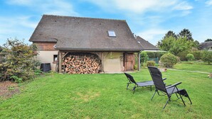 A house with a sloped roof, a wooden deck, and a stack of firewood in front.