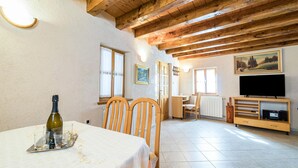 A dining area with a table set for two, wooden chairs, a wine bottle, and glasses on a tray. There is a television and a cabinet with electronic devices. - 2 bedroom cozy home in Zminj (Zminj)