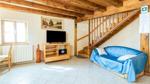 A wooden interior with a TV on a wooden stand, a blue sofa, a staircase, and a painting on the wall. - 2 bedroom cozy home in Zminj (Zminj)