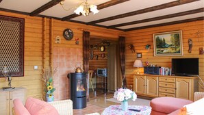 Een knus blokhutinterieur met een open haard, rieten meubels, een televisie en diverse decoraties.