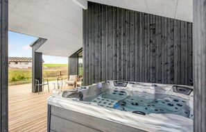 Relax in a tranquil outdoor space with a hot tub, surrounded by a deck and patio area with comfortable seating.