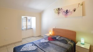 A bedroom with a bed, a nightstand, a bedside table, a window, and a painting on the wall. - 2 bedroom gorgeous apartment in Monte Isola (Monte Isola)